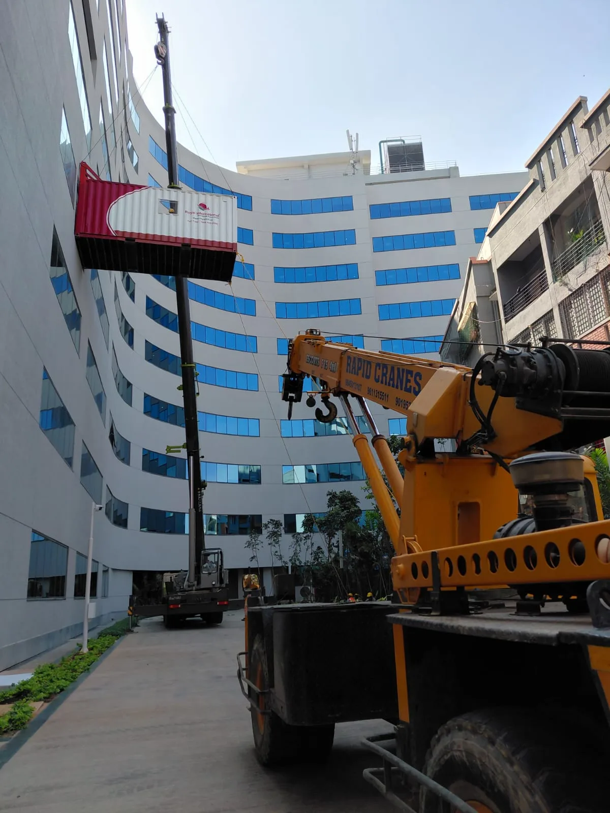 Rapid Cranes equipment lifting a container beside a building