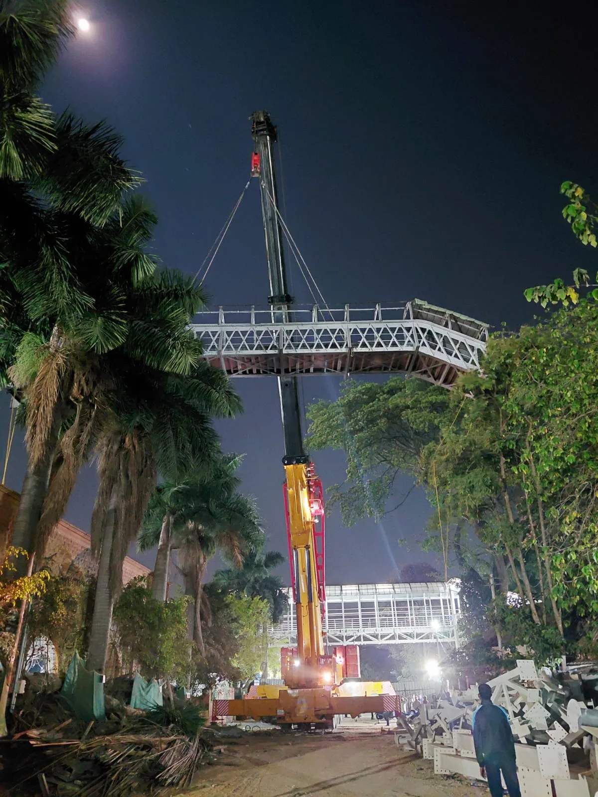 Crane lifting a steel walkway at night