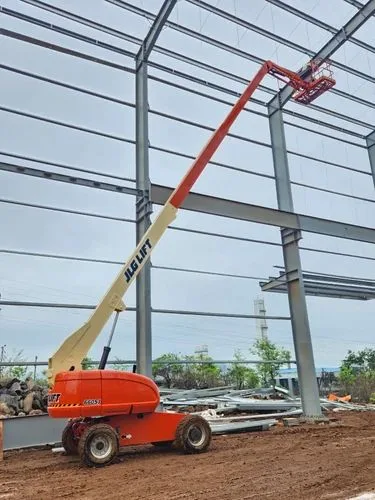 Orange boom lift raised inside a steel building frame