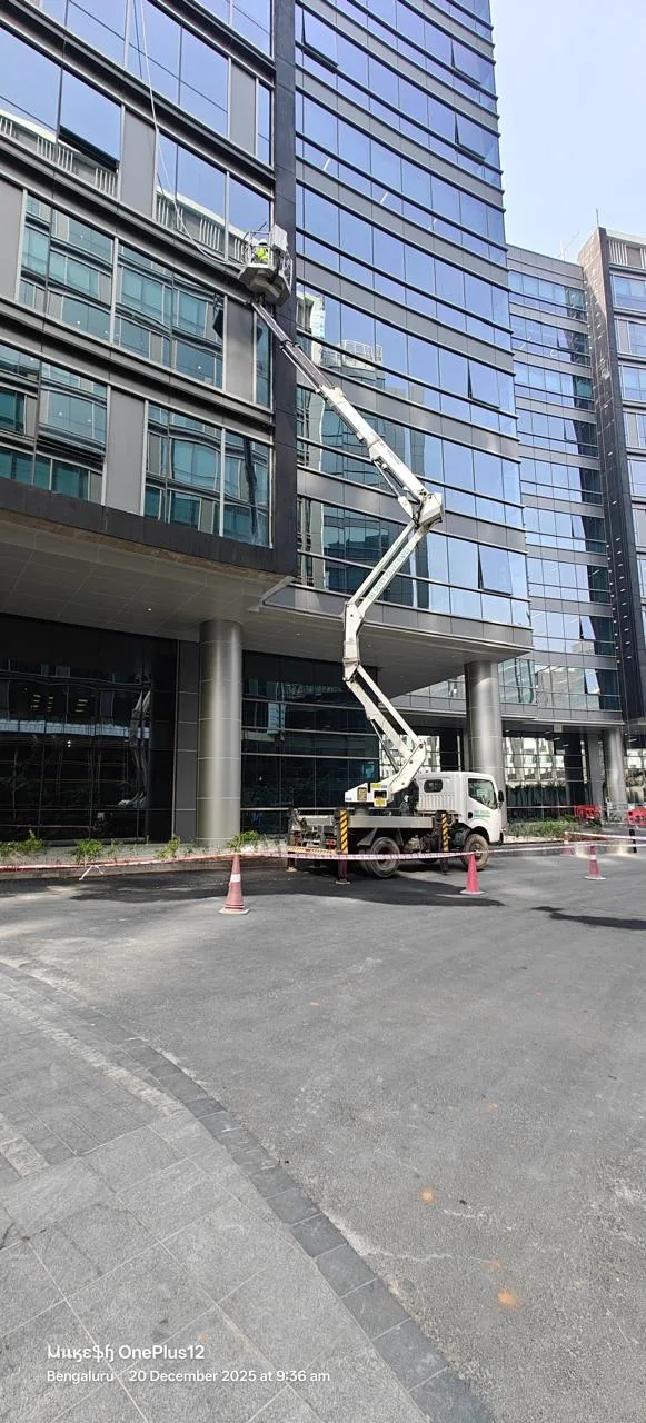 Truck-mounted access platform raised beside a glass-fronted building